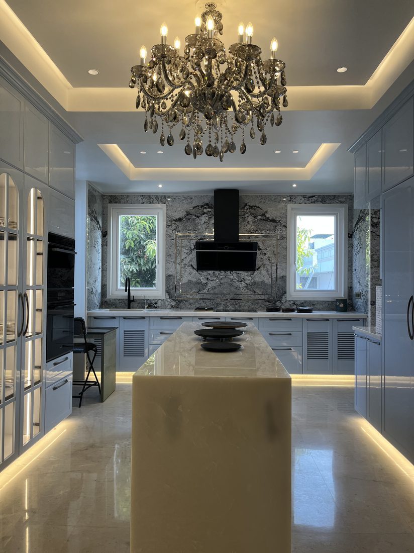 A marble kitchen island beneath a crystal chandelier in a Jaipur home